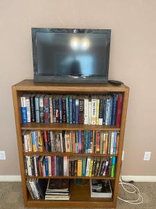 einen TV auf einem Bücherregal voller Bücher in der Unterkunft Private room in Awesome Sonoma Ranch Home in Las Cruces
