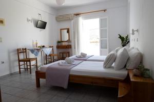 a bedroom with a bed with white sheets and a window at Seample studios in Chrissi Akti