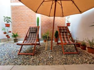 Duas cadeiras e um guarda-sol num pátio em Kasanty House em Paracas