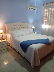 a bedroom with a white bed with a blue blanket at El Arrayan in Tacuarembó
