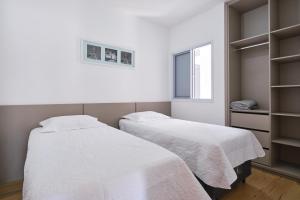 two beds in a room with white sheets at 2 QUARTOS com Churrasqueira na Varanda, Piscina, Garagem interna, WiFi 500mbps, Ar Condicionado e Telas de Proteção in Ubatuba