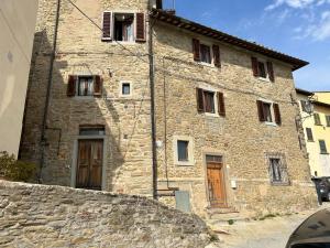 a stone building with two doors and a stone wall at La Casa di Laura in Cortona