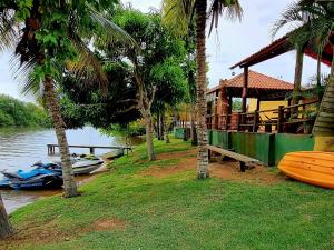 ein Haus mit einem Boot auf dem Wasser mit Palmen in der Unterkunft CASA AMARELA Beira Rio Guriri in Guriri
