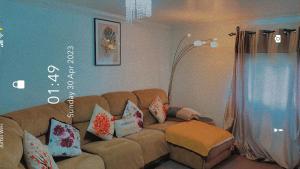 ein Wohnzimmer mit einer braunen Couch mit Kissen in der Unterkunft Lovely 2 Bed Flat/Apt in East London- Nice Estate. in Dagenham