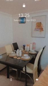 a dining room table with dishes on it with chairs at Lovely 2 Bed Flat/Apt in East London- Nice Estate. in Dagenham