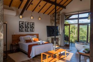 a bedroom with a bed and a tub and a television at Monte Mauá Chalés in Visconde De Maua