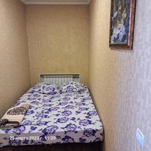 a bedroom with a bed with a purple and white comforter at Квартира 5-9 in Aktau