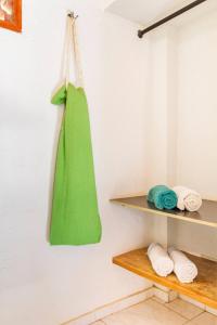 a green bag hanging on a wall next to towels at Casa Tara in Taganga
