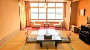 a living room with a table and chairs and a window at Aokiya in Sado