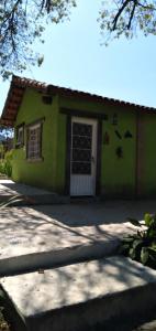 una pequeña casa verde con una puerta blanca en Pousada & Restaurante Chico Bento, en Lambari