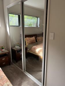 a mirror in a small room with a bed and a window at Guest Suite - Cosy place in the Wattle Downs in Auckland
