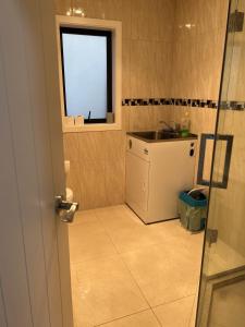 een kleine badkamer met een wastafel en een raam bij Guest Suite - Cosy place in the Wattle Downs in Auckland