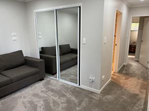 a living room with a couch and a mirror at Guest Suite - Cosy place in the Wattle Downs in Auckland