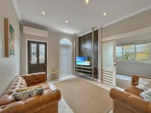 a living room with two couches and a flat screen tv at Bright 3-bedroom apartment - Central Armidale in Armidale