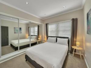 a bedroom with a large white bed and a mirror at Bright 3-bedroom apartment - Central Armidale in Armidale