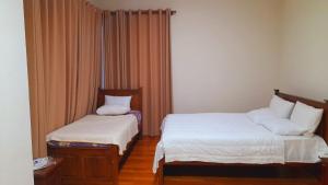 1 Schlafzimmer mit 2 Betten und weißer Bettwäsche in der Unterkunft LAKNA HOUSE in Colombo