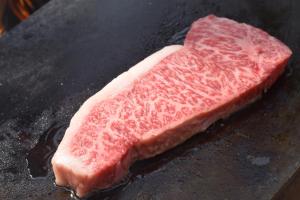 a piece of meat is cooking on a grill at Roots inawashiro Lake Area in Sekiwaki