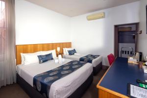 um quarto de hotel com duas camas e uma secretária em Central Hotel Hobart em Hobart