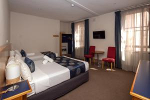 een hotelkamer met een bed en een tafel en stoelen bij Central Hotel Hobart in Hobart