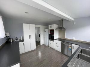 a kitchen with white cabinets and stainless steel appliances at Home with a view in Otorohanga