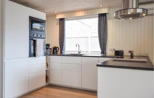 eine Küche mit weißen Schränken und einem Fenster in der Unterkunft 3 Bedroom Amazing Home In Otterup in Otterup