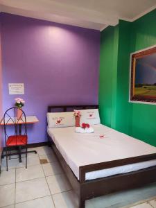 1 dormitorio con 1 cama con paredes moradas y verdes en WJV INN CANDUMAN, en Mandaue