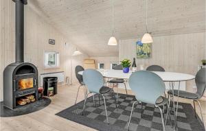 Habitación con mesa, sillas y chimenea. en Cozy Home In Nex With Sauna, en Bedegård