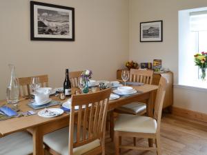 a dining room with a wooden table and chairs at Kilbride Beach Cottage in Pollachar