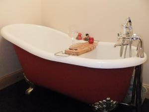 a bath tub with a sink and a wine glass at Kilbride Beach Cottage in Pollachar