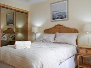 a bedroom with a white bed and a mirror at Kilbride Beach Cottage in Pollachar