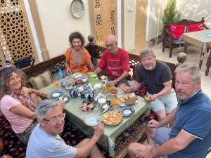 un grupo de personas sentadas alrededor de una mesa con comida en Habibi Bukhara, en Bukhara