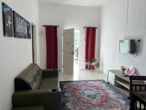 a living room with a couch and red curtains at Safiyya Homestay in Pantai Cenang