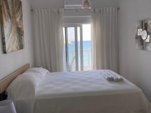 a bedroom with a bed with a view of the ocean at VILLA BLANCA in Haraki