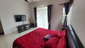 - une chambre avec un lit rouge et une télévision dans l'établissement Vision Homestay, à Seremban