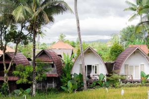 a group of cottages with palm trees at Damuh Pertivi in Lovina