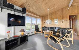 BjerregårdにあるLovely Home In Hvide Sande With Saunaのリビングルーム(テレビ、テーブル、椅子付)