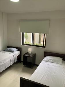1 dormitorio con 2 camas, ventana y mesa en Departamento Planta Baja con parqueo en Condominio en Santa Cruz de la Sierra