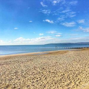 a sandy beach with a view of the ocean at Lovely Westbourne apartment - 15 min walk to beach in Bournemouth