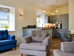 a living room with two chairs and a kitchen at Kingfisher Cottage in Kirkton of Airlie