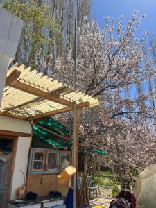 a wooden pergola on a house next to a tree at Napishu Summer Home in Leh