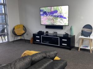 uma sala de estar com um sofá e uma televisão de ecrã plano em Titoki Grove em Cambridge