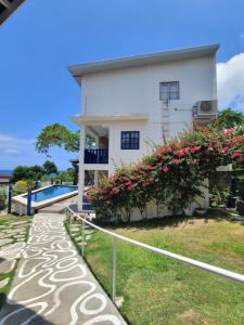 a white house with a swimming pool and flowers at BlueWoods Seaside Resort in Dauis