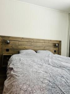 Skjomen Lodge في Elvegård: سرير مع اللوح الأمامي الخشبي ووسادتين