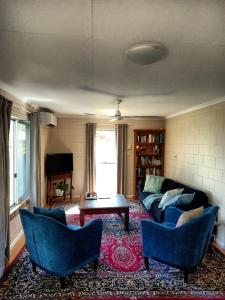 sala de estar con sofá, sillas y mesa en J & Ella's Holiday House - 2 Bedroom Stays en Cooktown