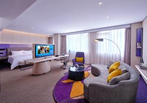 a hotel room with a bed and a couch and a television at Hampton by Hilton Shenzhen North Station in Shenzhen