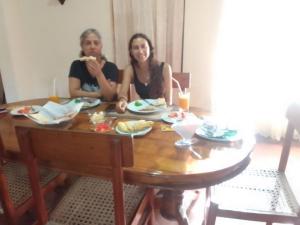 Duas mulheres sentadas à mesa a comer comida. em Mama's Hostel by Taprobane em Negombo