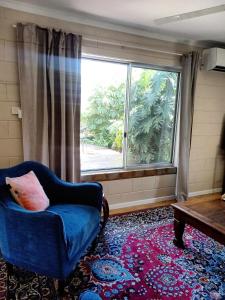 a living room with a blue chair and a large window at J & Ella's Holiday House - 2 Bedroom Stays in Cooktown