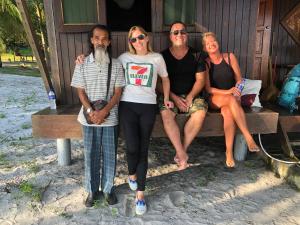 a group of three people sitting on a bench at Wild Pasir Panjang in Kuah