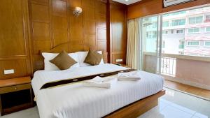 a bedroom with a large white bed with a window at Chalita House in Patong Beach