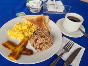 einen Teller mit Frühstücksfutter, Toast mit Eiern und eine Tasse Kaffee in der Unterkunft Hotel 1492 in San José